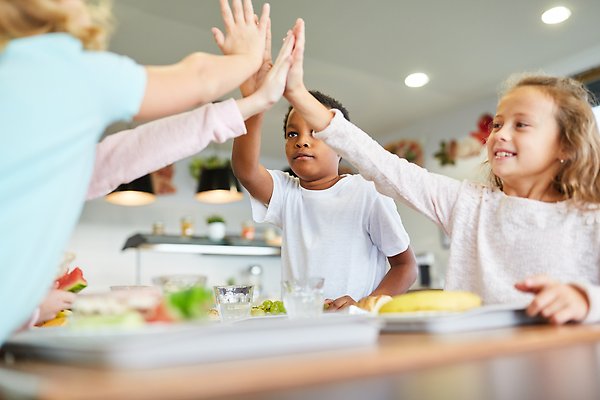 Skolbarn i matsalen gör high-five. Foto: Mostphotos.