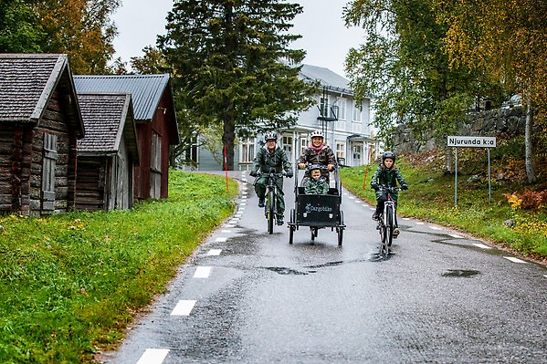 En familj cyklar ute i regnet.